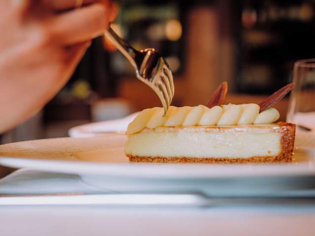 a slice of banana cream pie on a plate. model uses fork to get a bite.