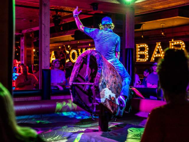 Images for a new venue coming soon to Pointe Orlando. Man riding a mechanical bull