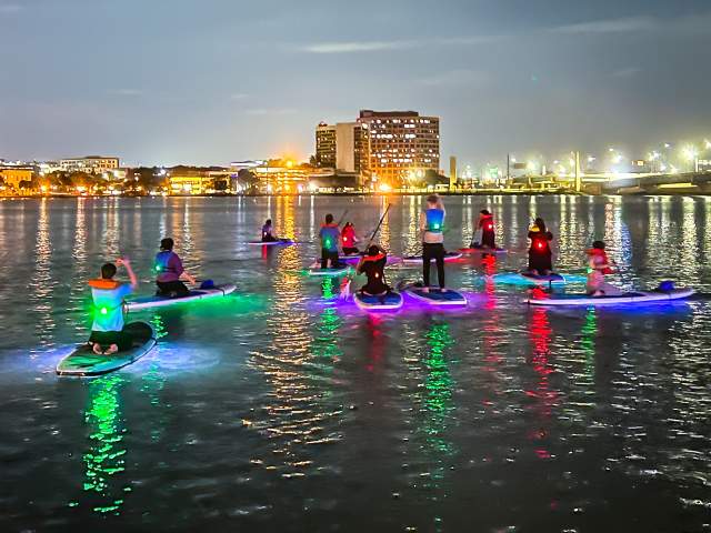 Paddleboarding at night near city with Epic Paddle Adventures