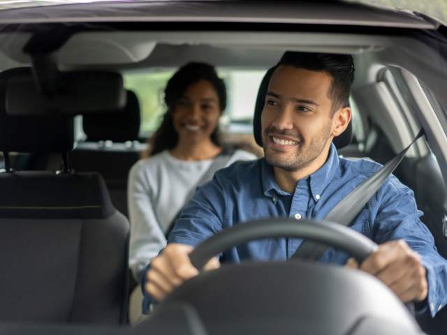 Latin American driver transporting a woman in a car while talking to her