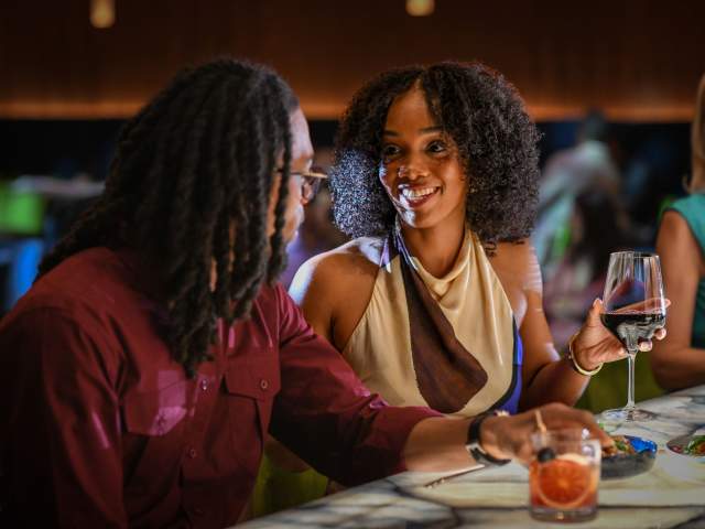 A couple chat with drinks in hand at the Judson's Live bar