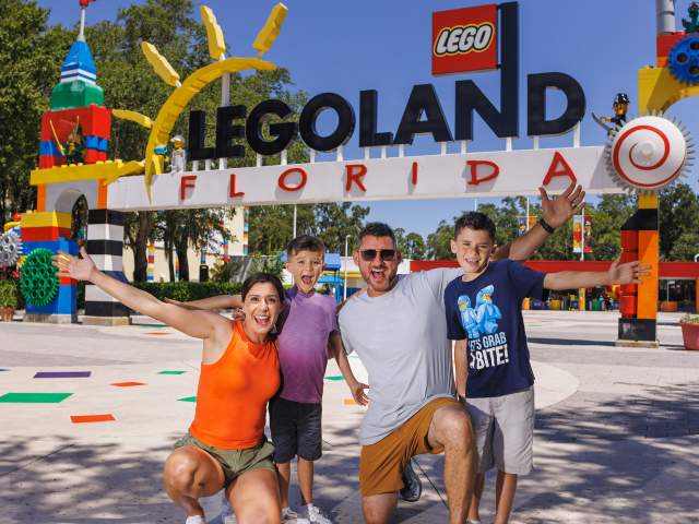 Mom, Dad and two sons smiling at the entrance to LEGOLAND Florida Resort