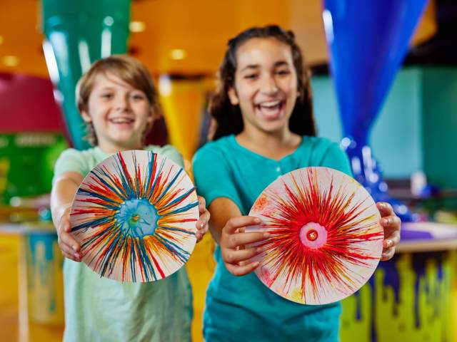 Two kids holding up their drip art at Crayola Experience