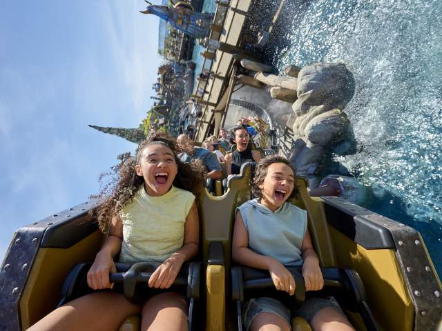 Children scream with laughter aboard Hiccup's Wing Gliders as the coaster swoops over the water in How to Train Your Dragon – Isle of Berk at Universal Epic Universe