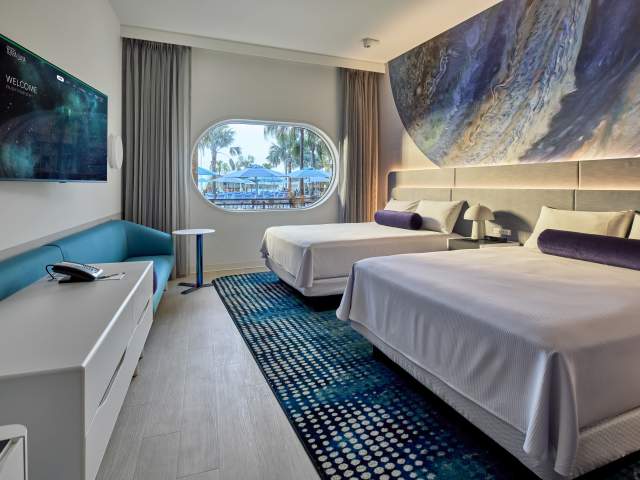 A pool-facing guest room with two queen beds and tranquil planetary elements at Universal Terra Luna Resort