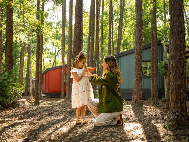 Mom and daughter looking at a butterfly on the mom's hand.