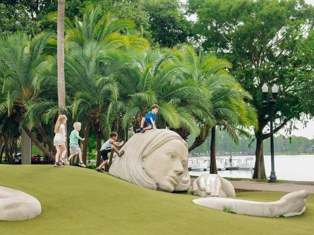 Children playing by the Muse of Discovery art at Lake Eola