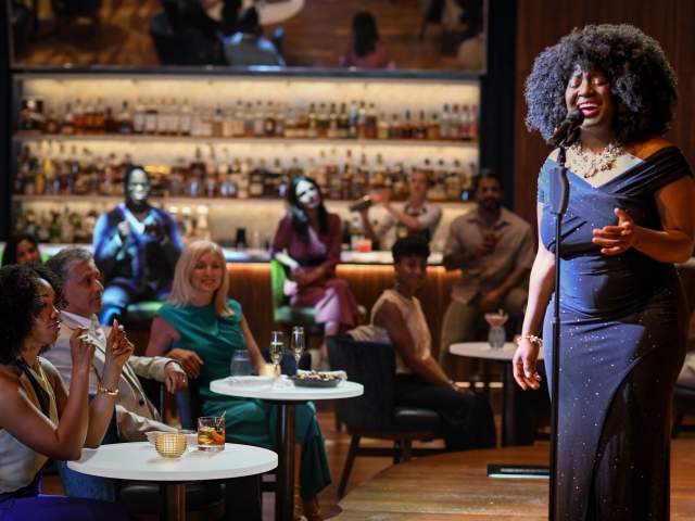 A woman sings onstage at Judson's Live while onlookers watch from intimate table and bar seating