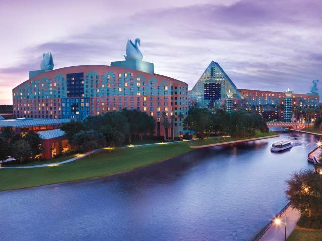 Exterior of resort with water taxi passing by at dusk at Walt Disney World Swan & Dolphin