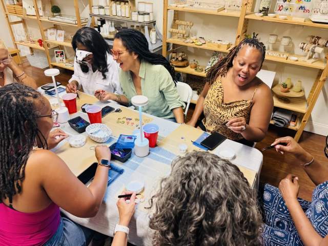 A group of women crafting and laughing around a table at Autumn & Ro