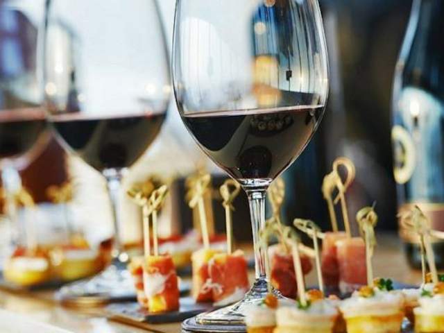 Bite sized appetizers and sample wine pours displayed on a table at a tasting event