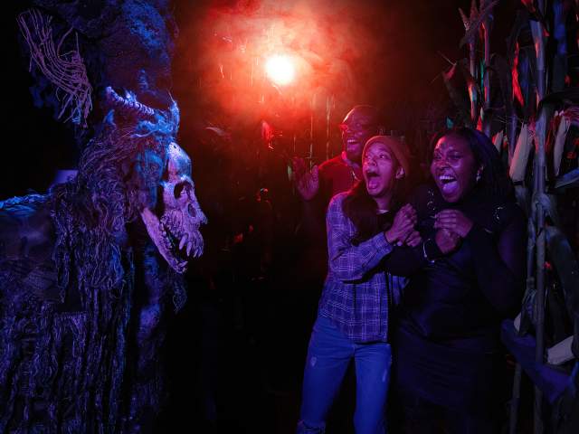 Friends scream and retreat from a masked figure at Halloween Horror Nights at Universal Orlando Resort