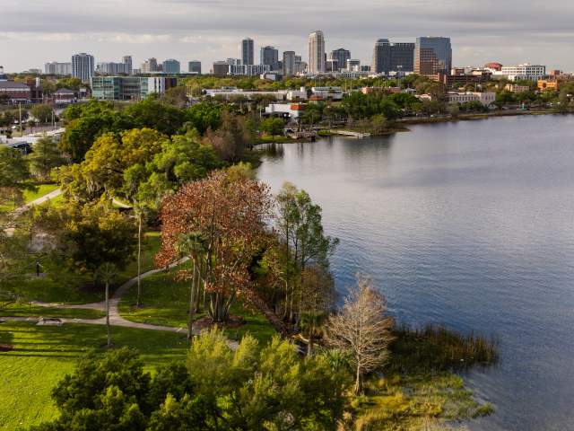 Aerial view of Lake Ivanhoe and its adjacent green space with the downtown Orlando skyline in the background