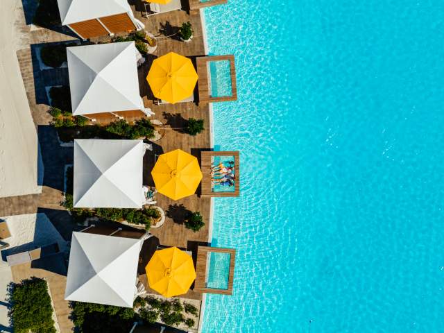 Aerial view of over-the-water cabanas with cheery yellow umbrellas at Evermore Orlando Resort