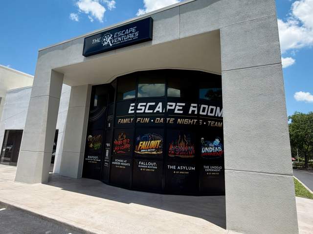 Exterior view of The Escape Ventures escape room attraction featuring branded signage, themed game graphics, and a modern storefront along International Drive in Orlando.