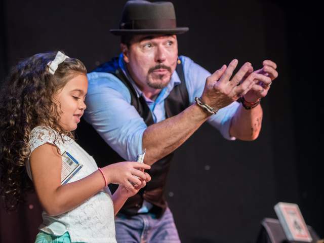 The Outta Control Magic Comedy Dinner Show card trick with child on stage