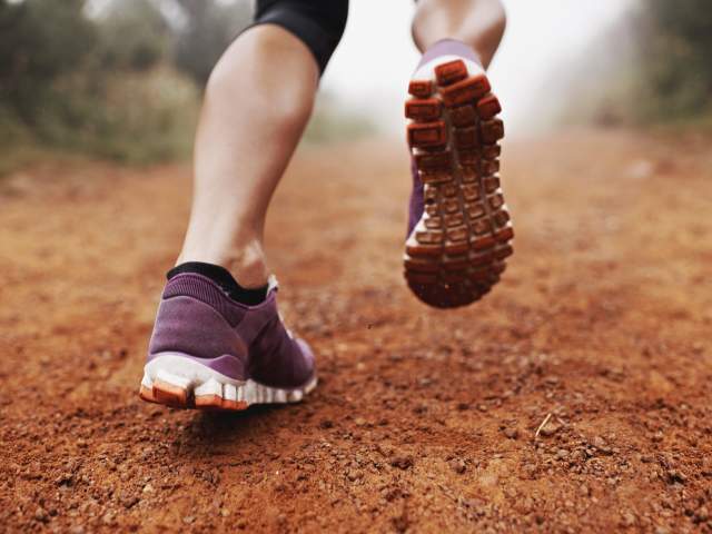 Closeup shot of a woman running on a dirt trail