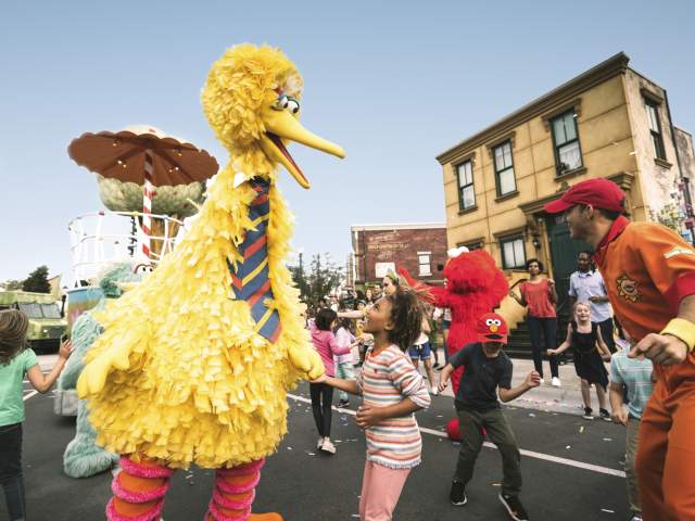 A little girl dancing with Big Bird in the Sesame Street Parade at Seaworld Orlando.