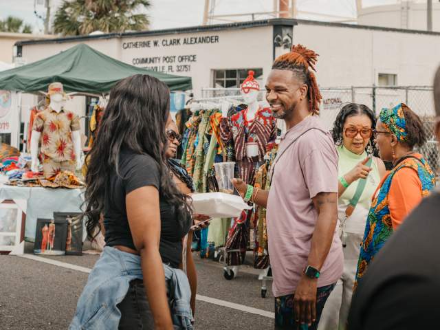 People smiling and chatting at the ZORA Outdoor Festival of the Arts in Eatonville
