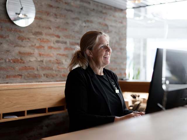 Smilende kvinnelig resepsjonist bak disken på Scandic City