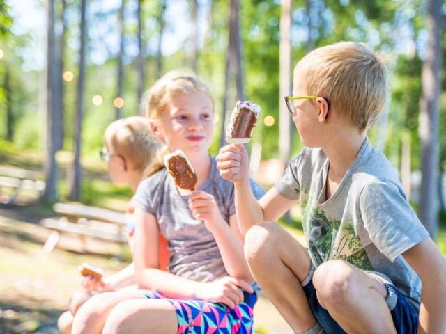 Tre barn sitter og spiser is