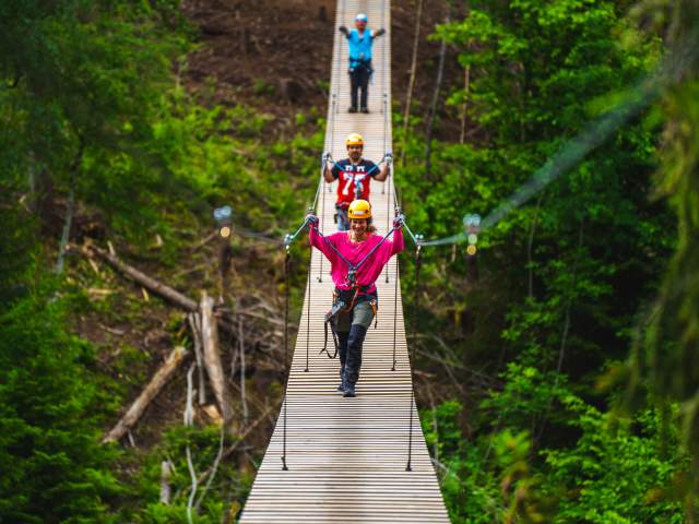 Tre personer på hengebroen i Via Ferrata Haldenkanalen