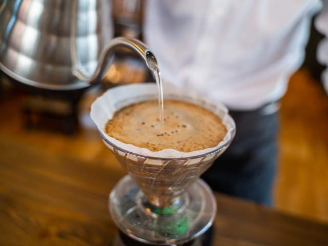 Person heller vann i en pour over-kaffekopp