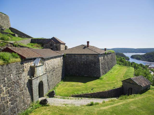 Fredriksten festning i Halden på sommeren med fjorden i bakgrunnen, grønt gress og blå himmel
