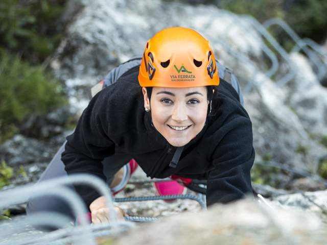 Ung kvinne med hjelp klatrer i Via Ferrata Haldenkanalen