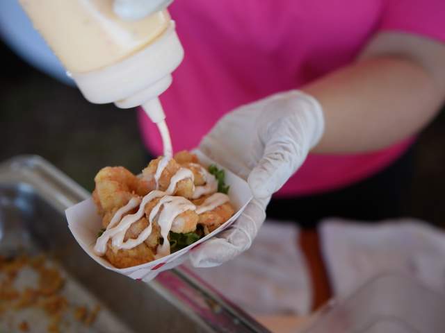 Person pouring sauce on food at the Outer Banks Seafood Festival