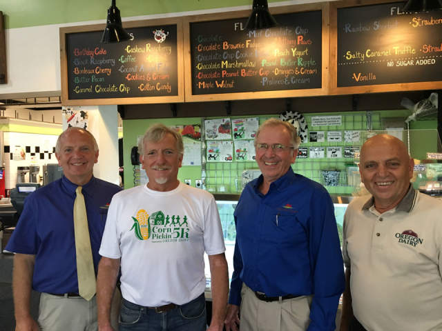 Four men posing for a photo in an ice cream shop with menus above them