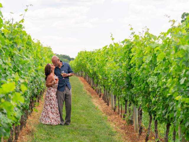 A man and woman kissing at a vineyard