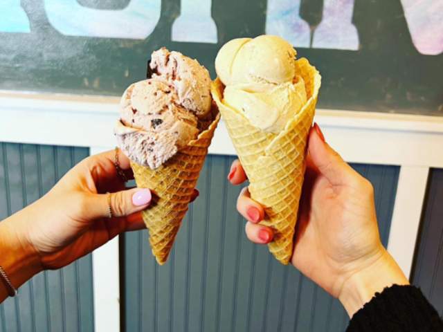 Two hands each holding up an ice cream cone with two scoops of ice cream