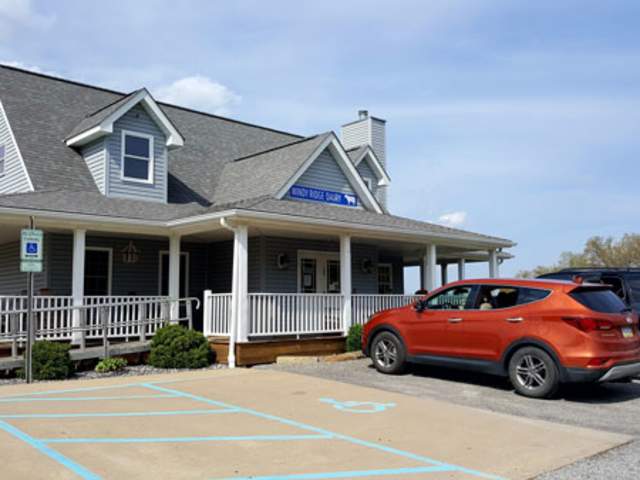 A red car parked in a parking lot in front of a creamery shop