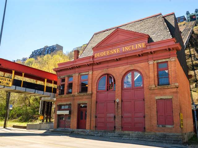 Exterior of a red historic building with two large arched doors that read Duquesne Incline