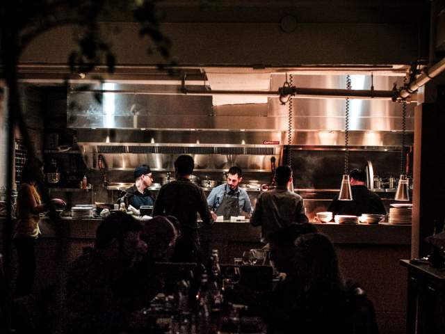 patrons enjoying food with kitchen view