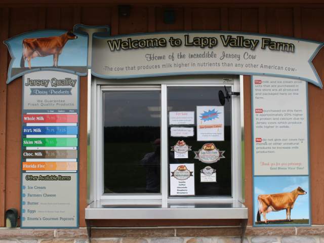 Exterior of a takeout window and a creamery with signage above that reads Welcome to Lapp Valley Farm with menus on either side of the window