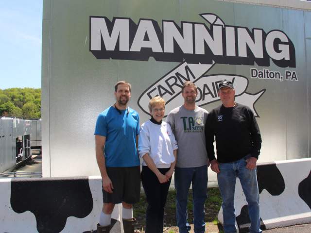 Four people standing in front of signage that reads Manning Farm Dairy