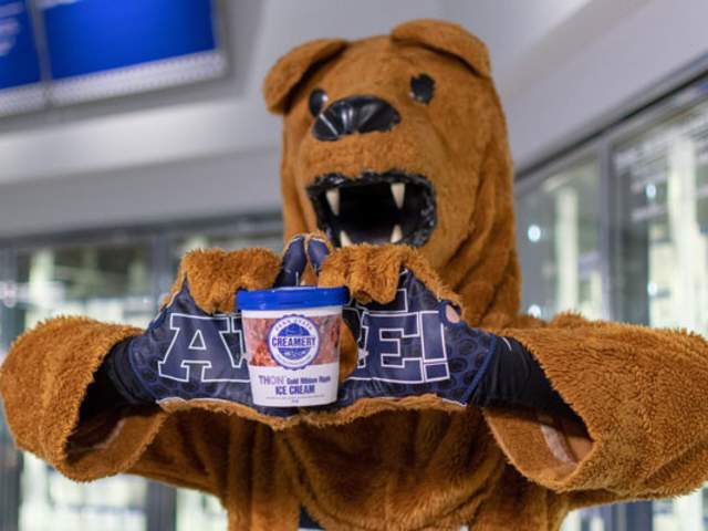 A lion mascot holding up a pint of ice cream