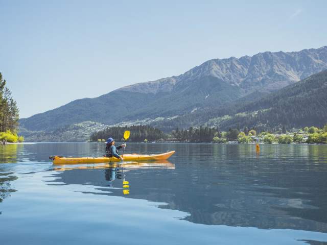 Person kayaking on Lake Whakutipu on a beautiful Spring day