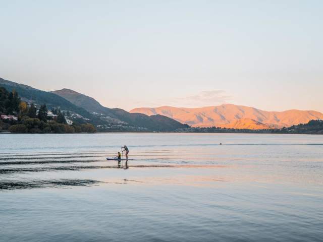 Paddleboarders in the middle of the lake at dusk