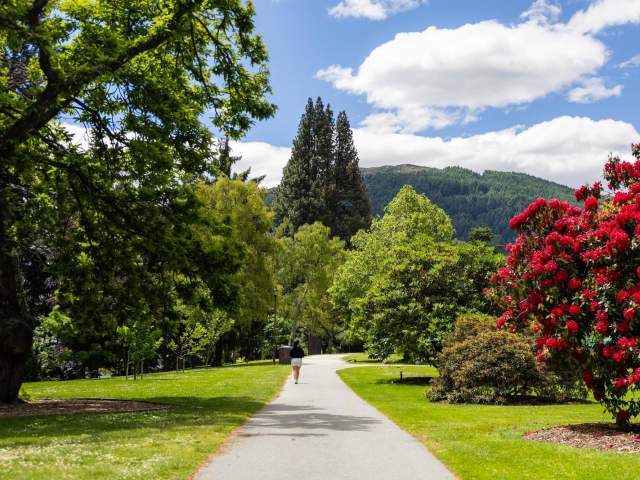 Queenstown Gardens Walk in summer with beautiful green and red trees and flowers
