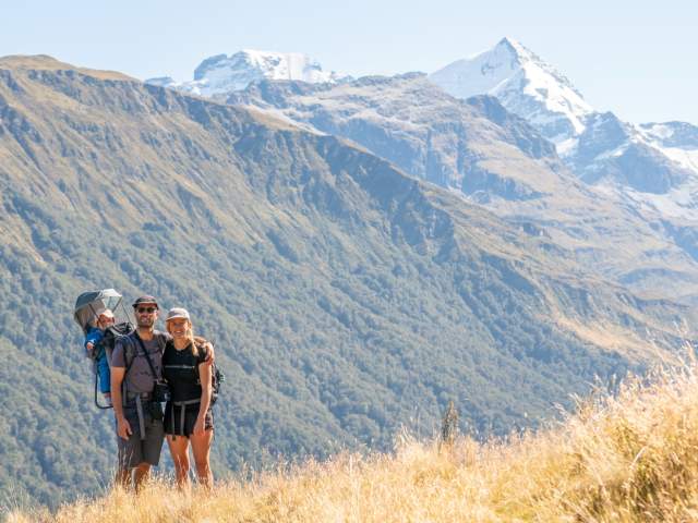 Pete Oswald, wife and baby on the Invincibles Track with snowy mountains in the background