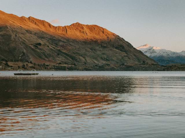 First snow of the autumn in Wānaka looking out on a bluebird morning with the sun rising on Roys Peak