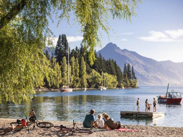 Family sitting by the waterfront looking out to lake and mountains