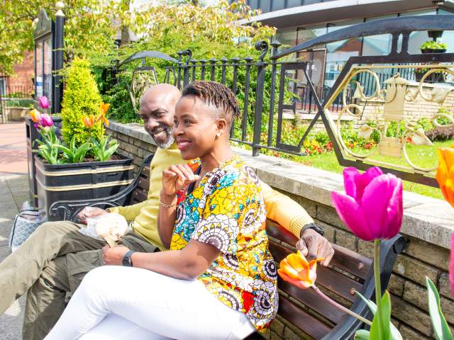 couple sit on bench by floral display diversity