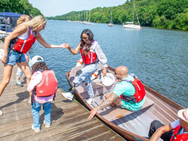 rowing boat visitor with prosthetic leg is helped out of boat