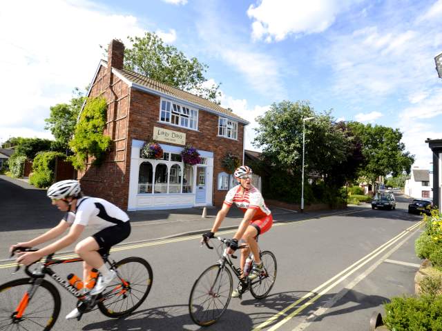 Brewood Village in South Staffordshire, two  men cycling  on  road
