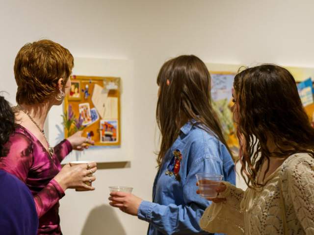 Four women view art in a gallery.