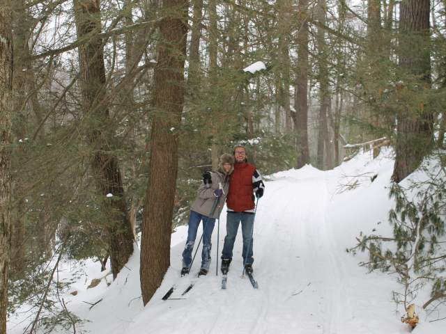 Couple Cross Country Skiing through snowy winter forest.